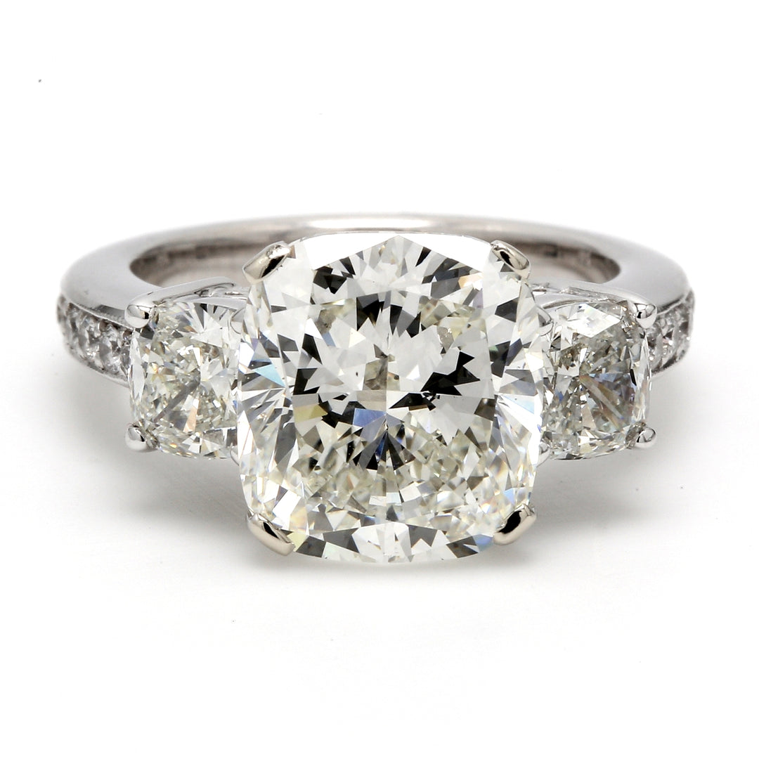 3-stone ring in 18K WG with prong set GIA certified J/SI2 cushion center, cushion sidestones, and pave set round diamonds on the shank. D8.19ct.t.w.