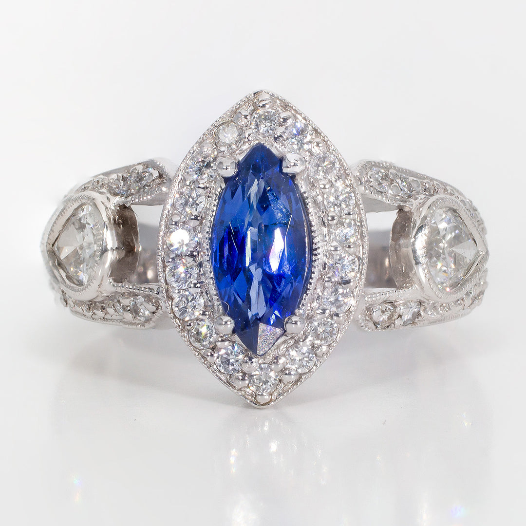 Halo ring in platinum with with bezel set pear shape sides, pave set round diamonds around 4-prong set marquise shaped sapphire center stone. D1.20ct.t.w. Sapphire 1.04ct.
