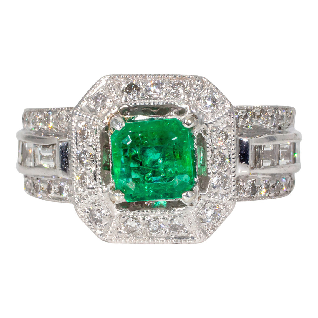 Halo ring in platinum with pave set rounds, channel set baguette diamonds and 4-prong set emerald center stone. D1.10ct.t.w. Emerald 0.86ct.