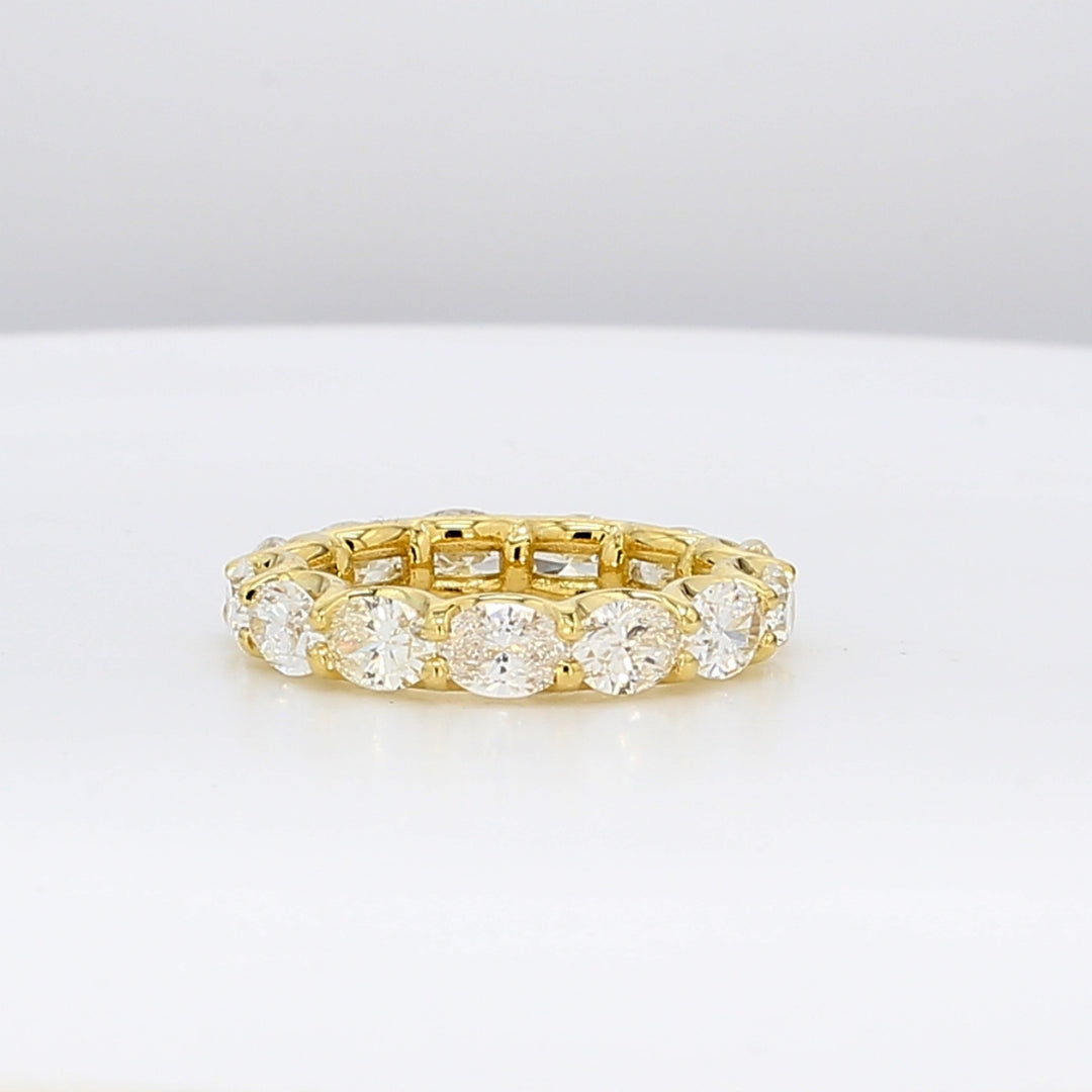 East to west style eternity band in 18K YG with 4-prong set (13) oval cut diamonds. D3.43ct.t.w. Size 5