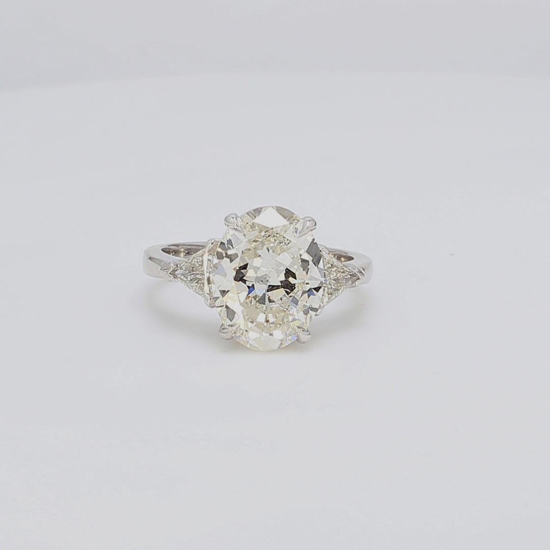 3-stone ring in platinum with GIA certified J/SI2 oval center and trilliant diamond sides. D5.52ct.t.w. (Center 5.01ct.)