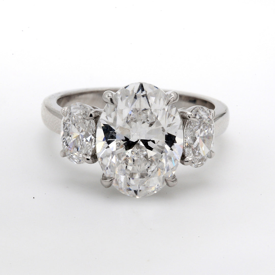 3-stone ring in platinum with GIA certified D/SI2 oval center and prong set oval diamond sides. D5.14ct.t.w. (Center 4.09ct.) Size 6