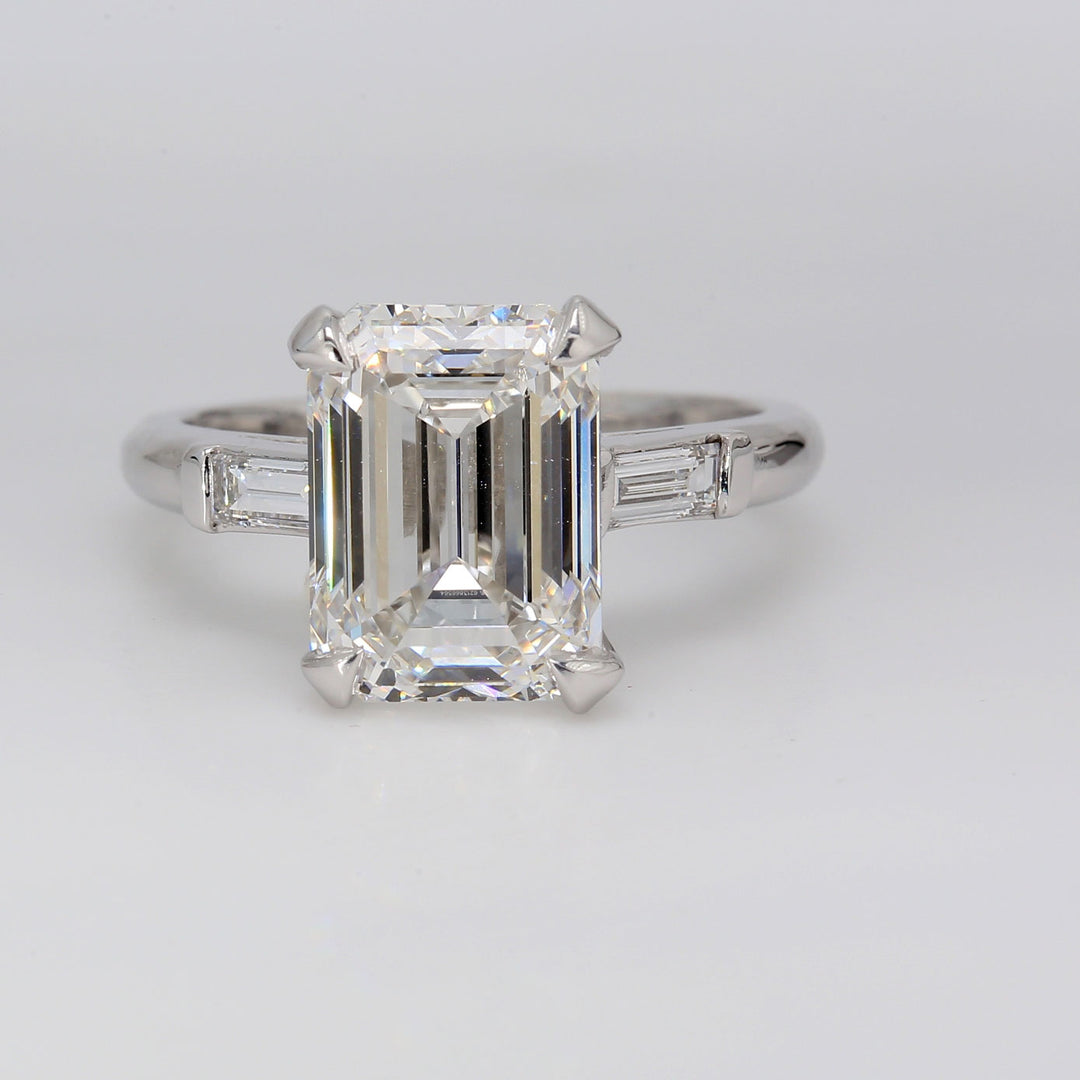 3-stone ring in platinum with prong basket set GIA certified E/VS2 emerald cut center and channel set baguette diamond sides. D5.29ct.t.w. (Center 5.01ct.)