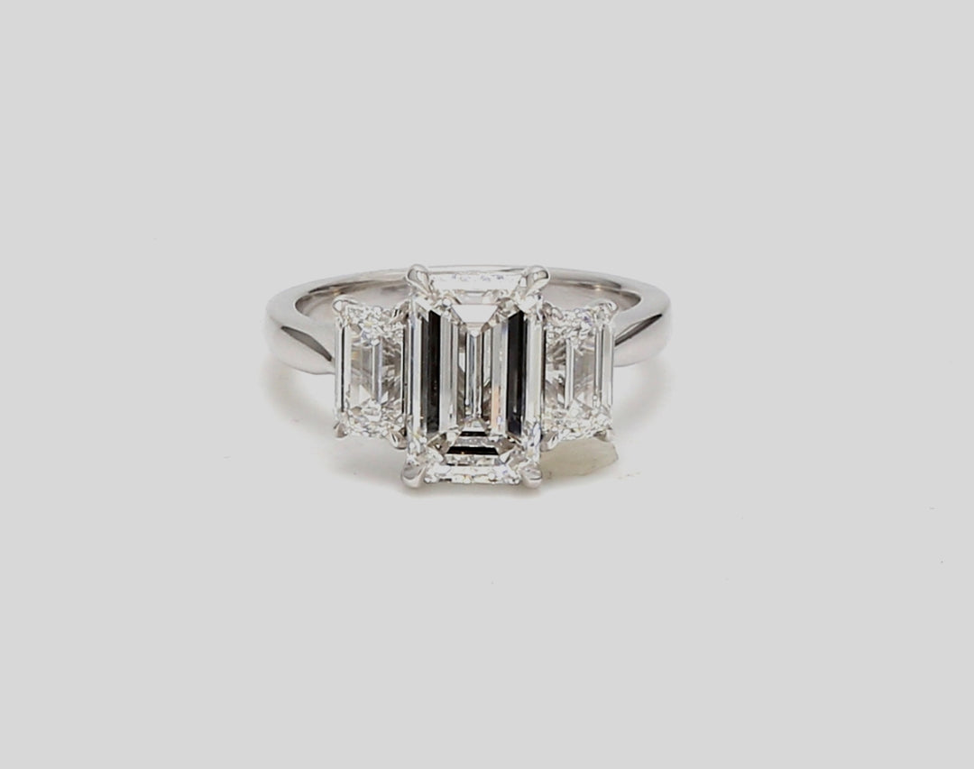 3-stone ring in platinum with GIA certified E/VS1 emerald centerstone and E/VS2 emerald cut diamond sides. D4.41ct.t.w. (Center - 3.01ct.)