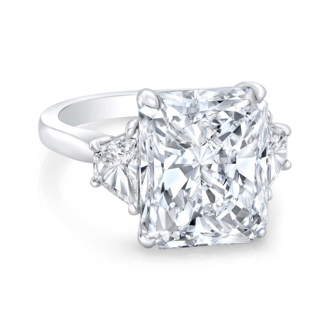 3-stone ring in platinum with prong set trapezoid sides and GIA certified F/SI1 radiant cut diamond center. D10.82ct.t.w. (Center - 10.02ct.) Size 6.75