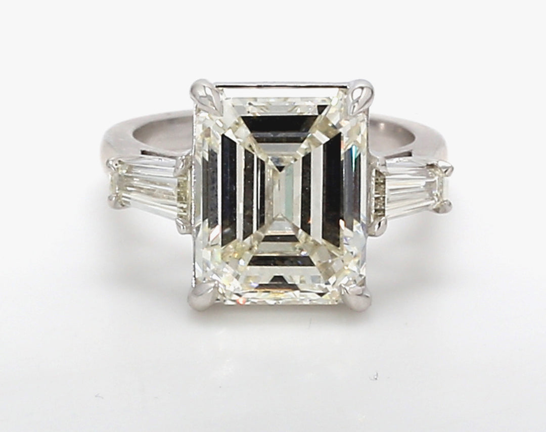 3-stone ring in platinum w/ basket claw prong set tapered baguette sides & GIA certified K/VS2 emerald diamond center. D7.76c.t.w. (Center - 7.07ct.) Size 6