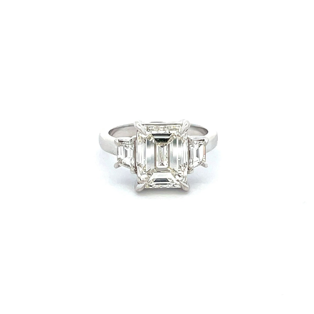 3-stone ring in platinum with GIA certified K/VS2 emerald cut center and 4-prong set step cut trapezoid diamond sides. D4.64ct.t.w. (Center - 4.01ct.)