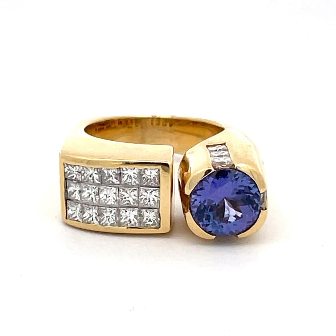 Ring with square shank in 18K YG with channel & 3-row invisible set princess cut diamonds and bezel set tanzanite center.  D3.15ct.t.w.  (Tanzanite - 1.61ct.)
