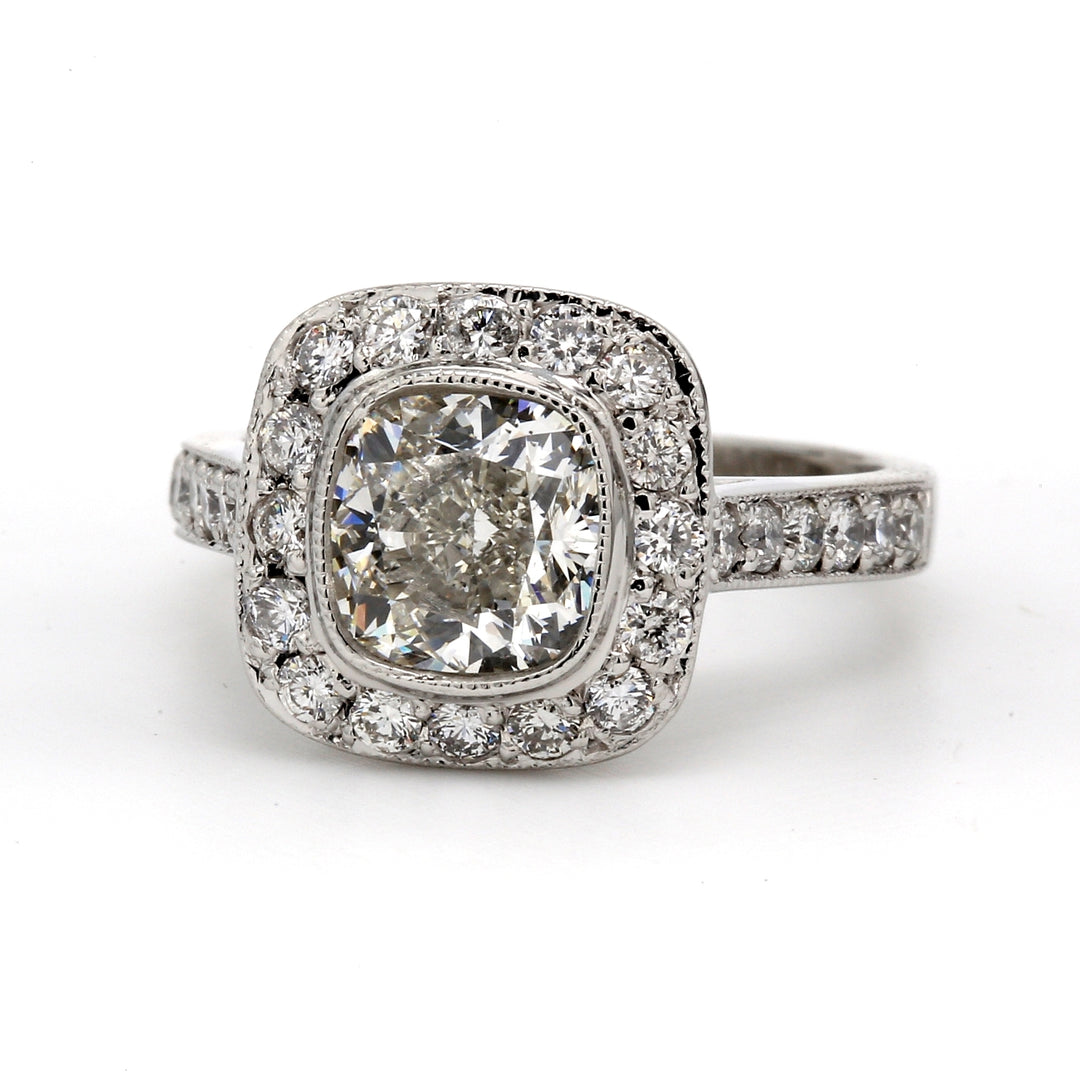 Halo ring in platinum with bezel set USA certified G/SI1 cushion cut center and pave set round diamonds.  D2.92ct.t.w.  (Center 2.02ct.)  Size 6.5