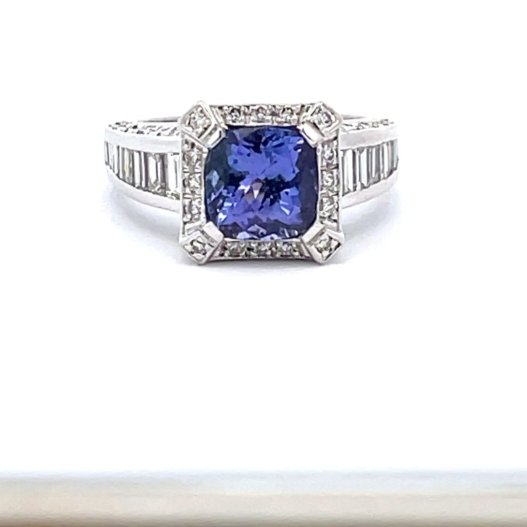 Halo tapered shank ring in 18K WG with channel set baguettes, pave set round diamonds and 4-prong set Tanzanite center.  D1.41ct.t.w.  (Tanzanite - 2.10ct.)