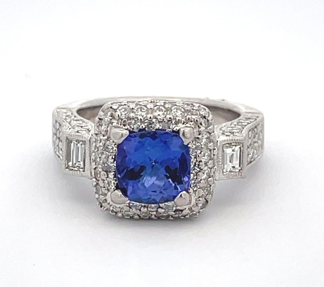 3-stone halo ring in platinum with bezel set baguettes, pave set round diamonds and 4-prong set cushion shape tanzanite center.  D1.55ct.t.w.  (Tanzanite - 1.50ct.)