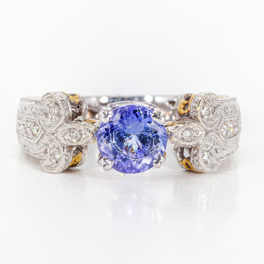 Designer fleur-de-lis ring in 18K two-tonewith bezel and pave set round diamonds, and 4-prong set round tanzanite center stone.  D0.30ct.t.w.  Tanzanite 1.43ct.