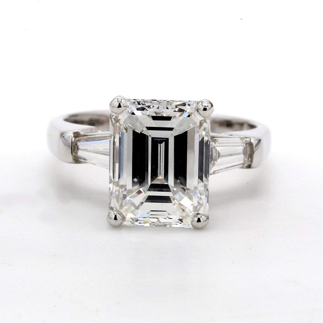 3-stone ring in platinum withchannel set tapered baguette diamonds  on each side and emerald cut center in   prong set.  D2.55ct.tw (CTR 2.00)  Center stone is GIA certified and graded  as K / VS2