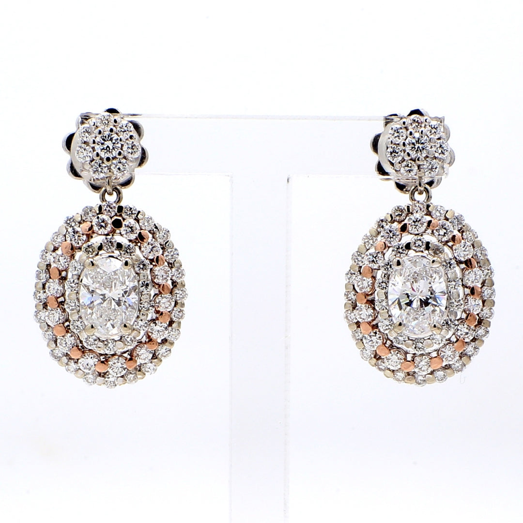 Halo dangling earrings in two-tone with shared prong set rounds & 4-prong set oval diamond centers.  D2.50ct.t.w.  (Centers 1.10ct.t.w.)