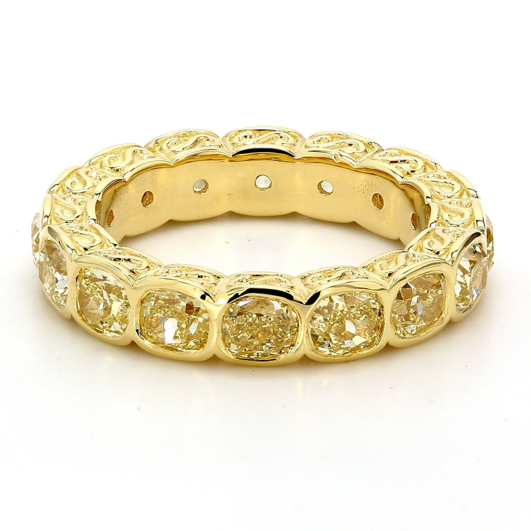 Eternity band in 18K YG with fleur-de-lis design on the sides, & bezel set (16) fancy yellow cushion diamonds.  D4.60ct.t.w.