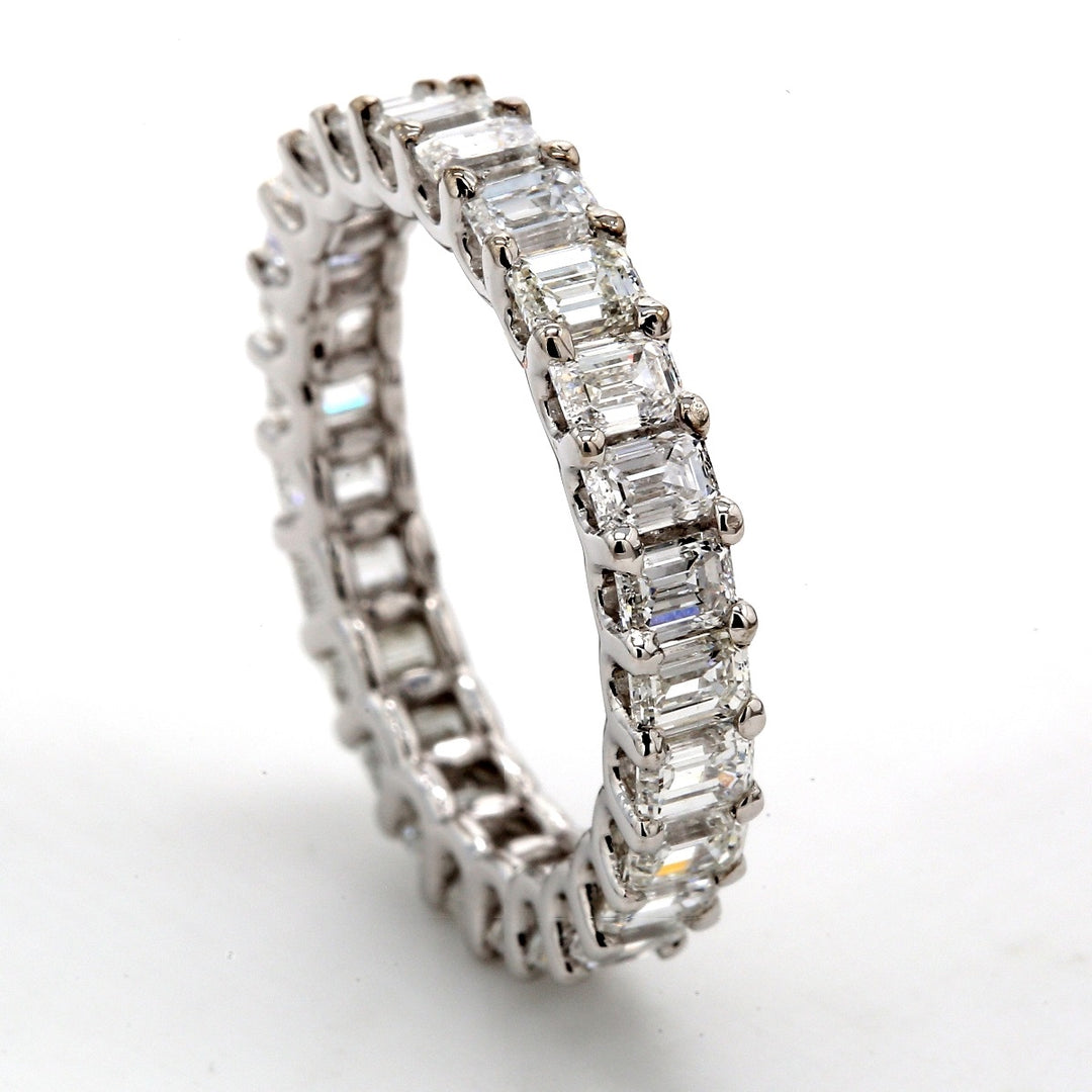 Eternity band in platinum with shared U-prong set emerald cut diamonds.  D5.89ct.t.w.