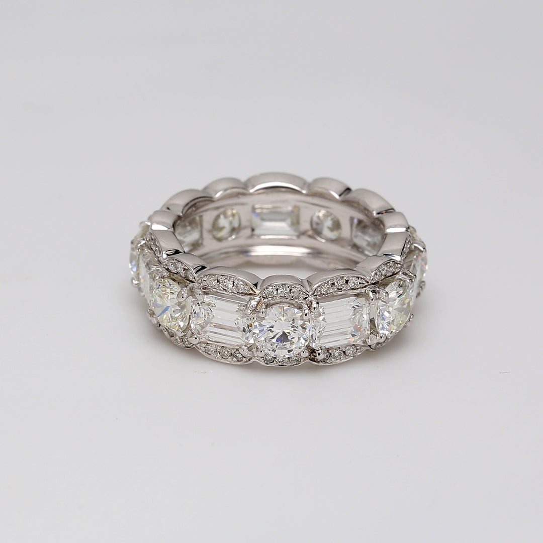 Eternity band with prong set alternating rounds and emerald cuts & pave set round diamonds on the sides.  D4.34ct.t.w.  Size 4