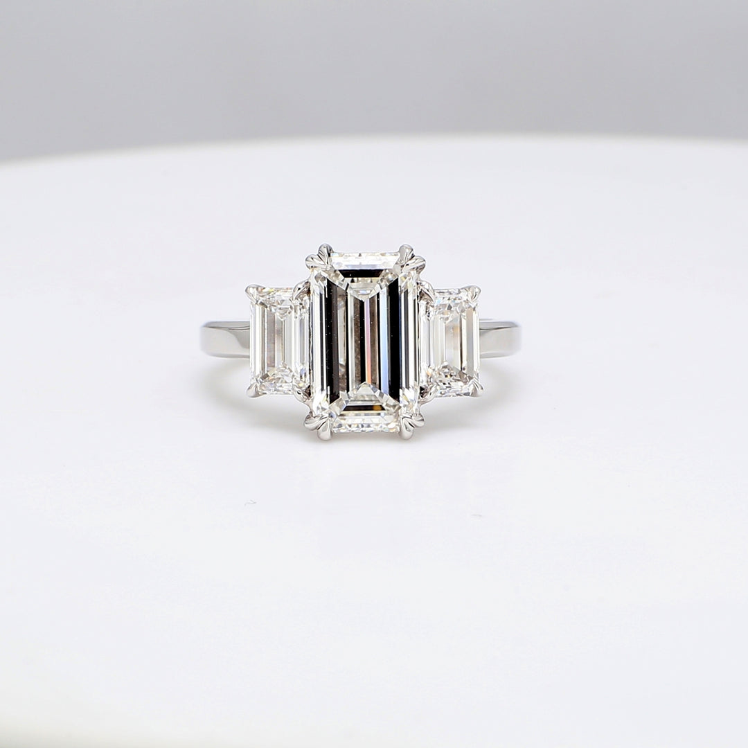 3-stone ring in platinum with GIA certified F/VVS1 emerald cut center and E/IF-VVS1 emerald diamond sides.  D4.45ct.t.w.  (Center 3.00ct.)