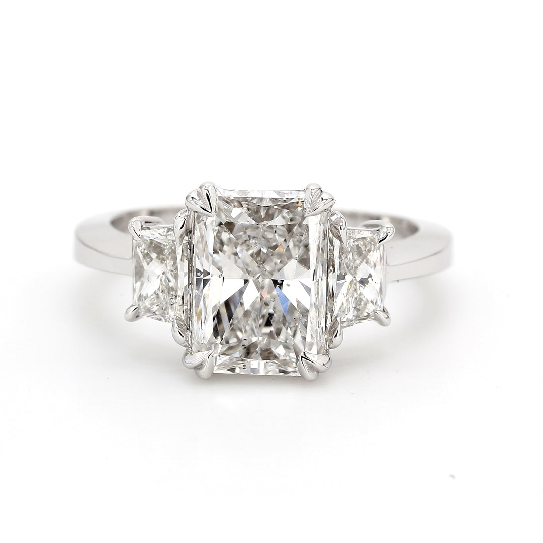 3-stone ring in platinum with GIA certified E/SI1 radiant center and prong set trapezoid diamond sides.  D3.84ct.t.w.  (Center - 3.01ct.)  Size 6.5