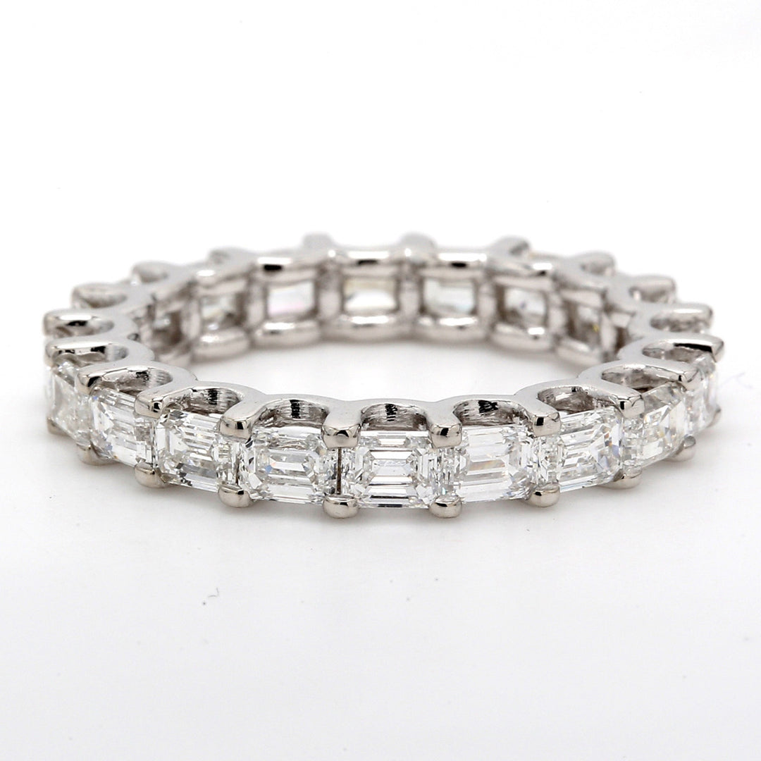 East to west style eternity band with shared U-prong set emerald cut diamonds.  D3.37ct.t.w.