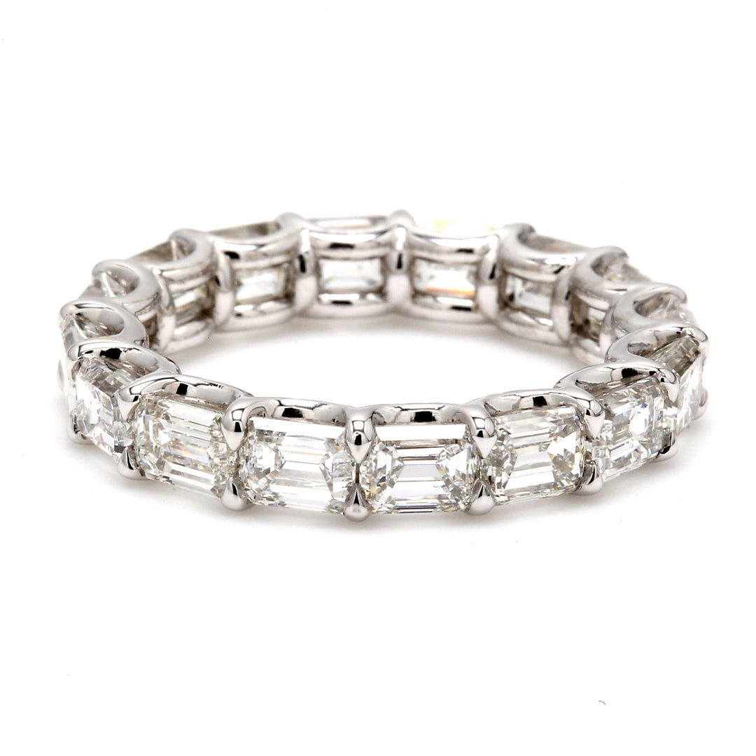East to west style eternity band in platinum with shared U-prong set emerald cut diamonds.  D4.82ct.t.w.  Size 5.75