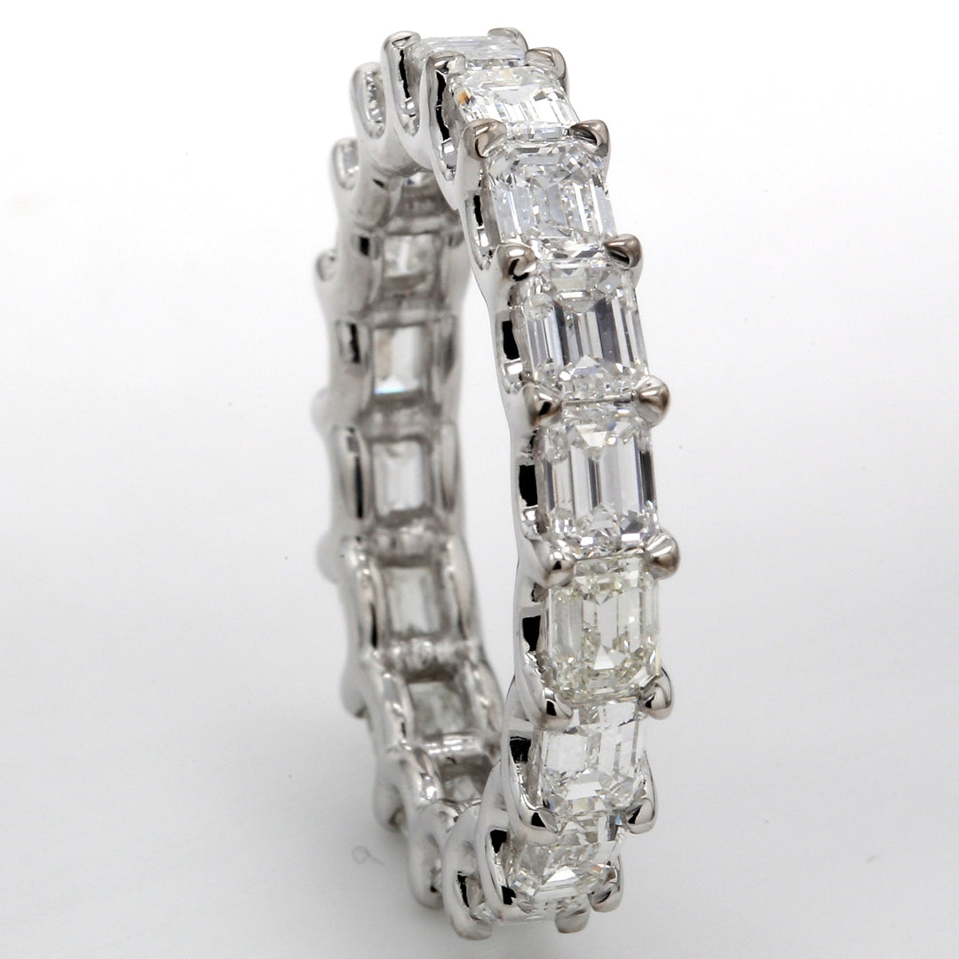 East to west style eternity band with shared U-prong set F-G/VS emerald cut diamonds.  D3.65ct.t.w.  Size 6