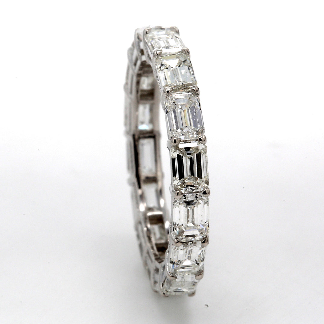 East to west style eternity band in 18K WG with basket prong set (16) emerald cut diamonds.  D3.10ct.t.w.  Size 5