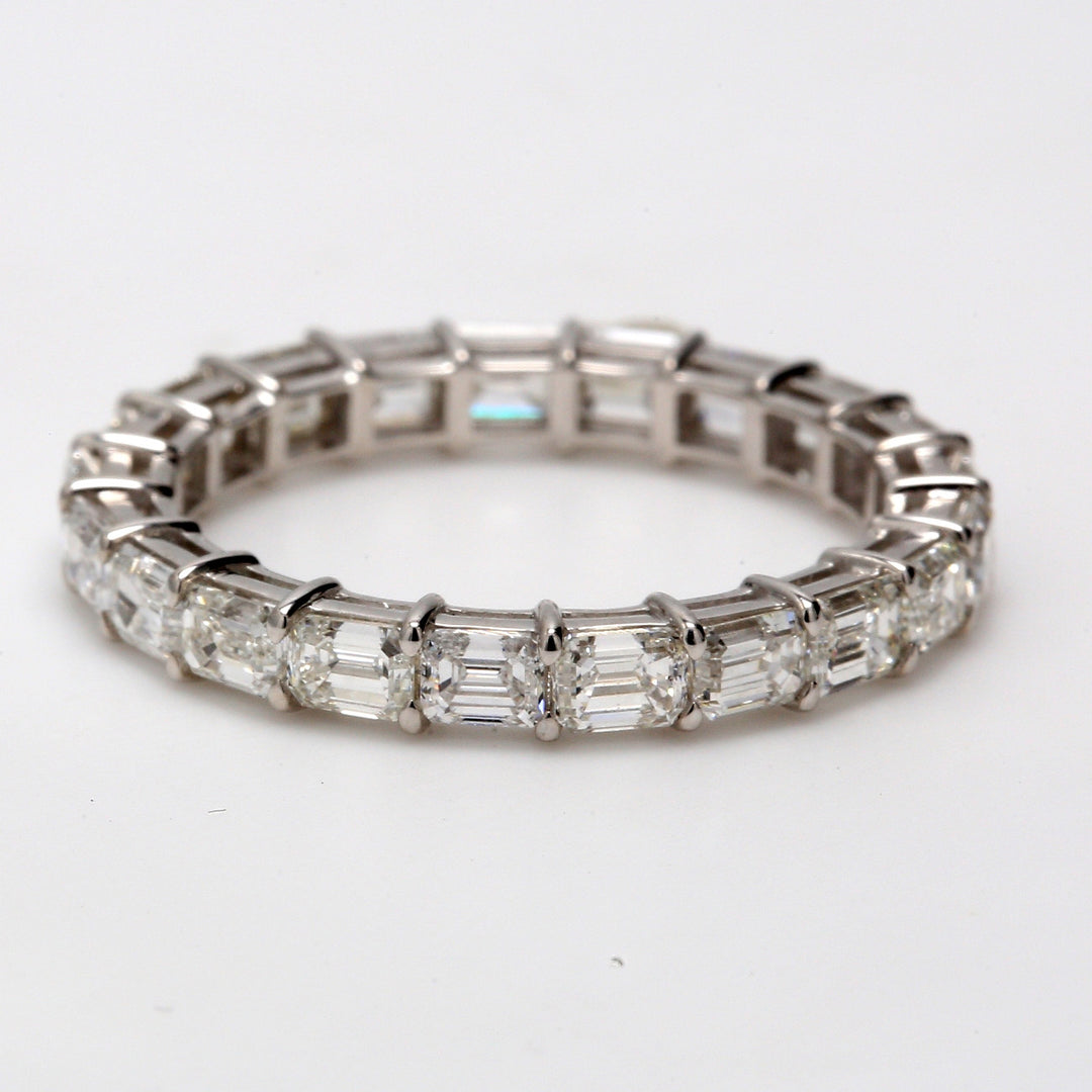 East to west style eternity band in 18K WG with shared prong set (17) emerald cut diamonds.  D2.71ct.t.w.  Size 5.5