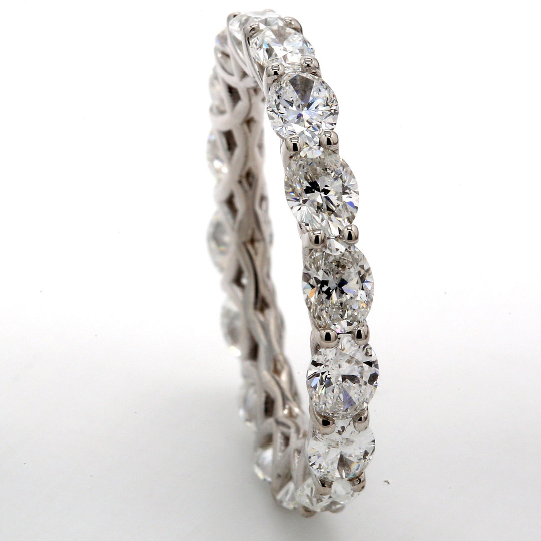 East to west style eternity band in 18K WG with prong set (16) oval diamonds.  D3.36ct.t.w.  Size 6.75