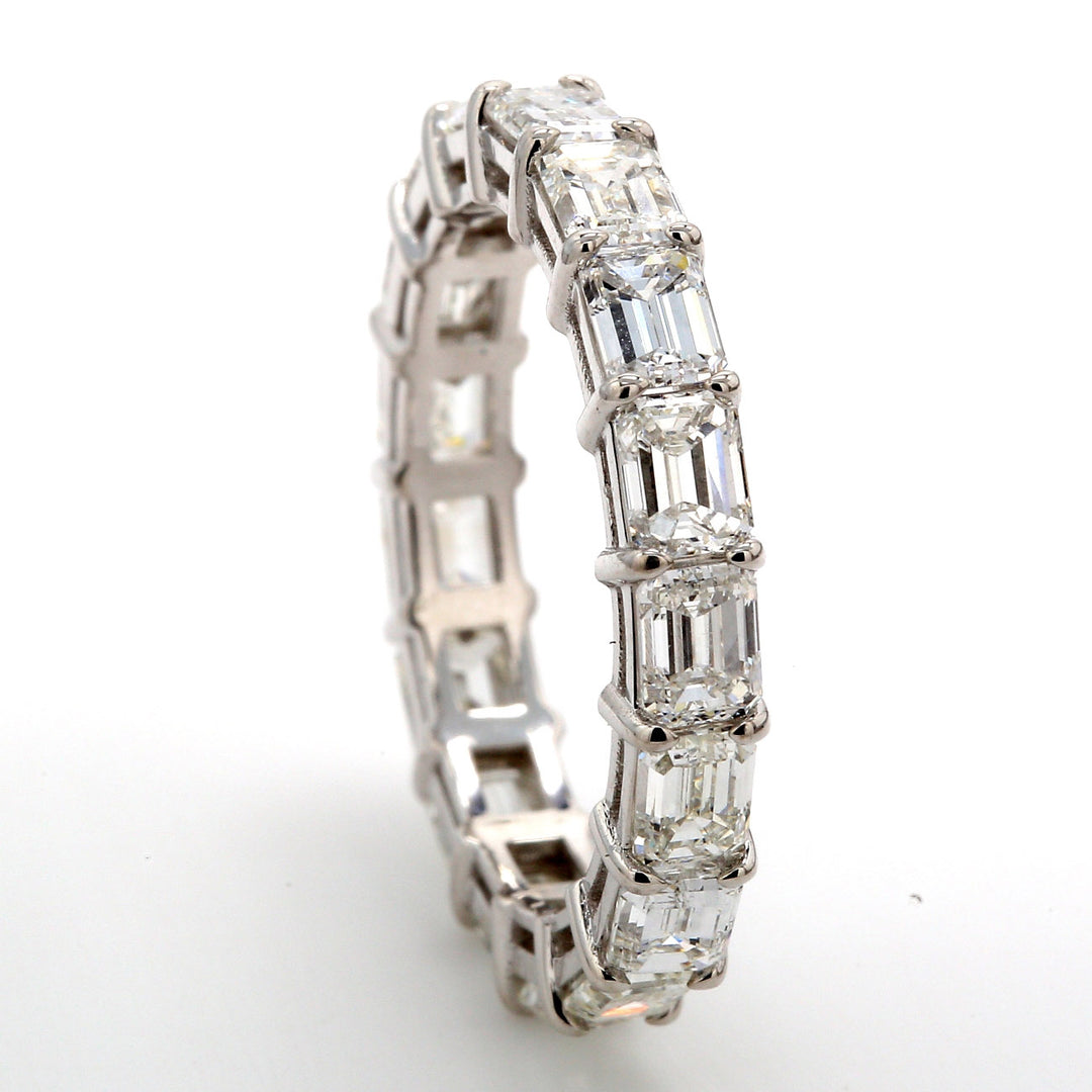 East to west style eternity band in 18K WG with prong set (17) emerald cut diamonds.  D3.39ct.t.w.  Size 6