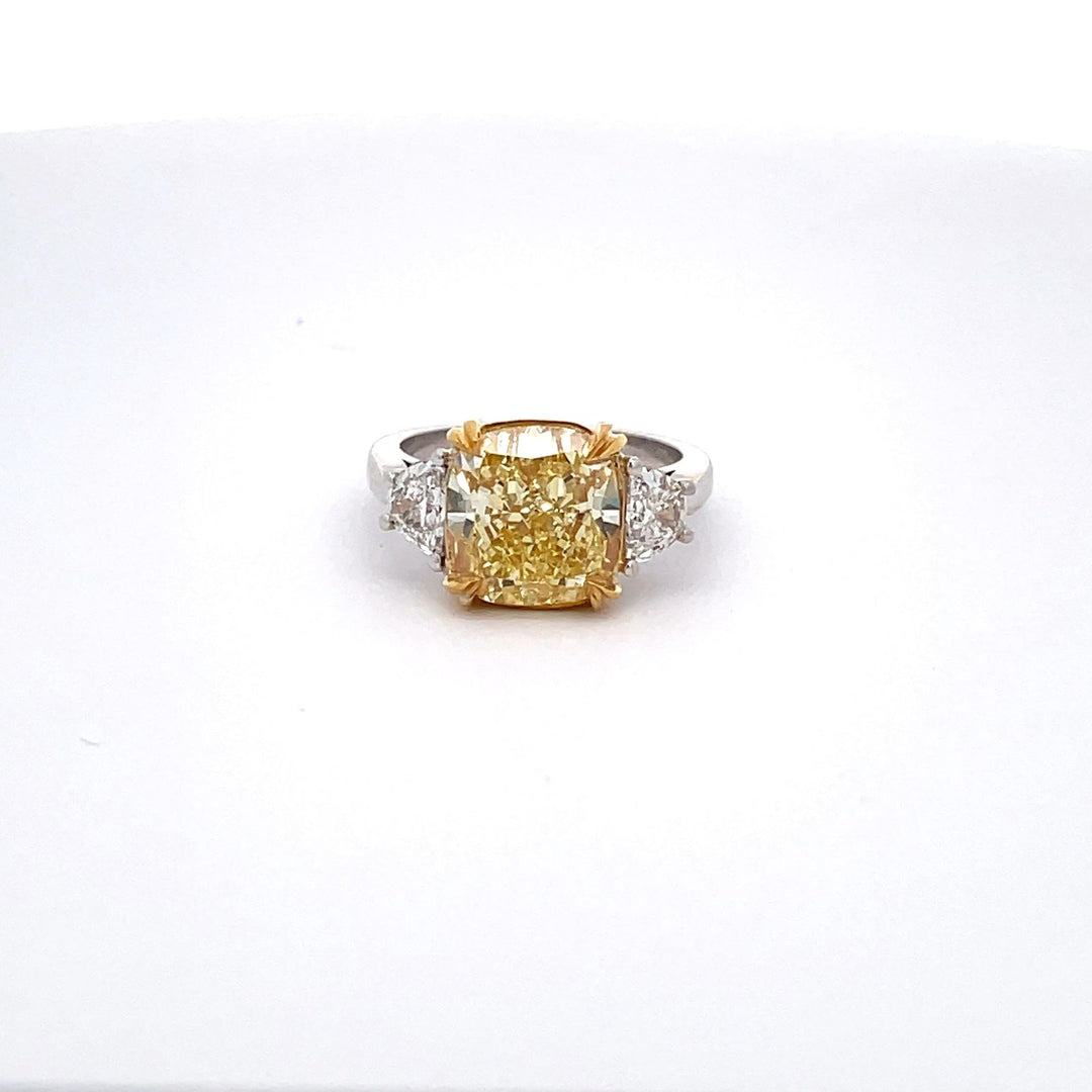 3-stone ring with 4-prong set half moon sides & claw 4-prong set GIA certified FIY/VS1 cushion cut center.  D5.70ct.t.w.  (Center - 5.05ct.)