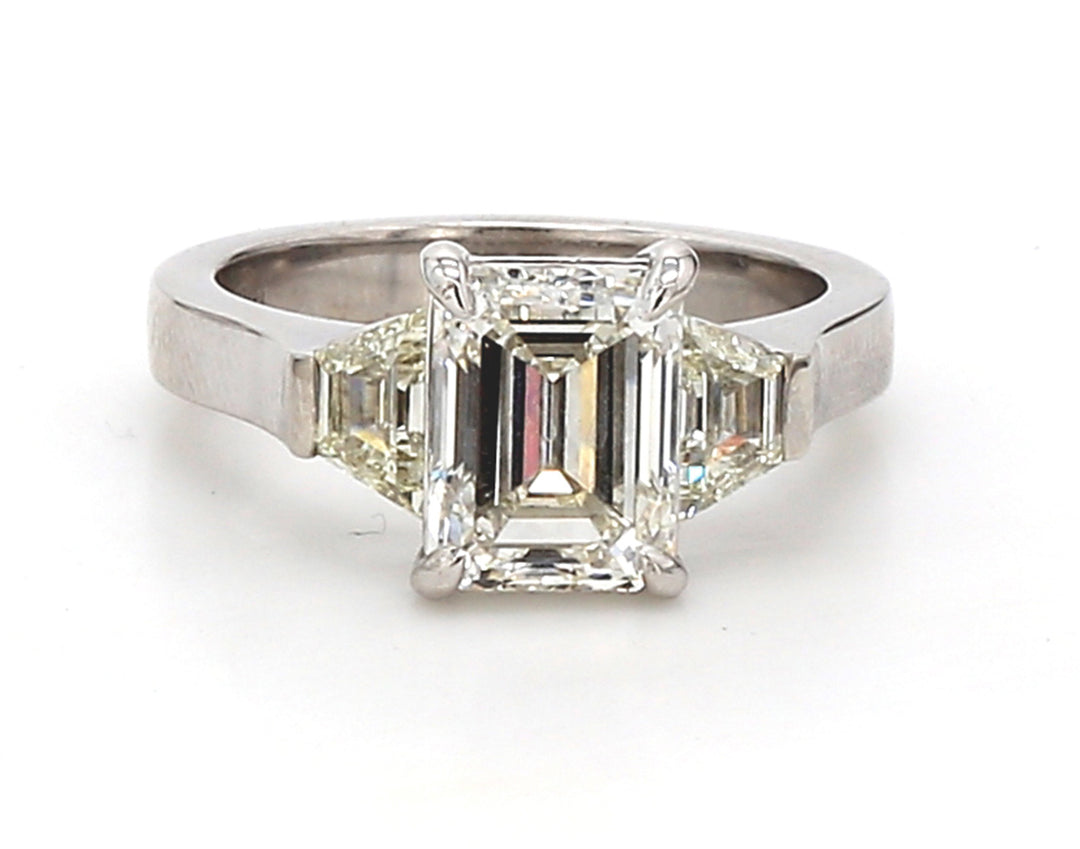 3-stone ring in platinum with GIA certified J/VS2 emerald cut center and trapezoid diamond sides.  D3.07ct.t.w.  (Center - 2.50ct.)  Size 6